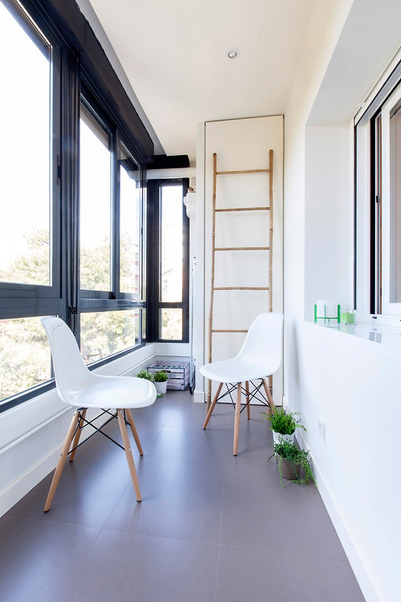 R de Room INTERIORISMO MADRID. Proyecto de reforma para una vivienda al sur de Madrid. Terraza acristalada con sillas Eames blancas y escalera de bambú de House Doctor.