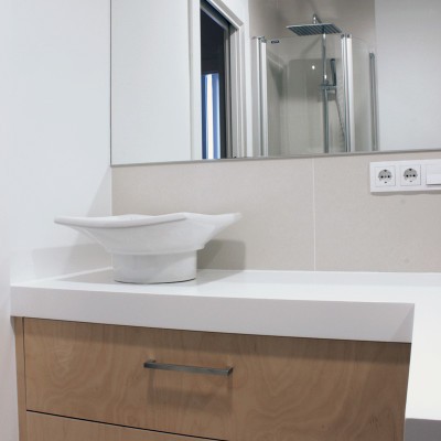 En el baño en suite del dormitorio ganado a la zona de servicio se necesitaba una gran superficie de trabajo. Como las dimensiones del baño eran reducidas, diseñamos un mueble a medida que optimizara el espacio.
