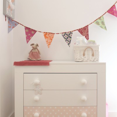 El dormitorio infantil se decoró en tonos rosa con elementos como banderines, lámparas nube, etc.