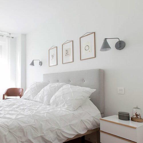 Proyecto de R de Room Amazing Homes. Dormitorio principal de diseño nórdico con cabecero tapizado en gris, mesillas de noche blancas.