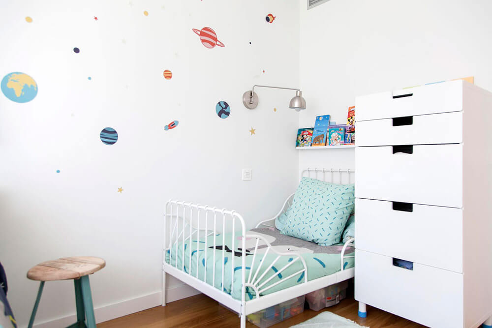 Proyecto de R de Room Amazing Homes. Dormitorio infantil con cama nido y cama extensible blancas y decoración inspirada en el universo.