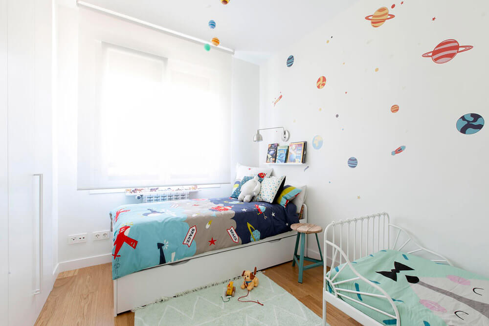 Proyecto de R de Room Amazing Homes. Dormitorio infantil con cama nido y cama extensible blancas y decoración inspirada en el universo.