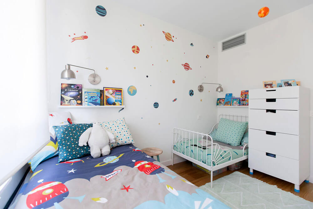 Proyecto de R de Room Amazing Homes. Dormitorio infantil con cama nido y cama extensible blancas y decoración inspirada en el universo.