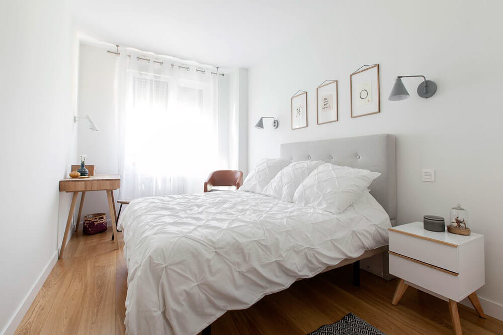 Proyecto de R de Room Amazing Homes. Dormitorio principal de diseño nórdico con cabecero tapizado en gris, mesillas de noche blancas y tocador de madera maciza.