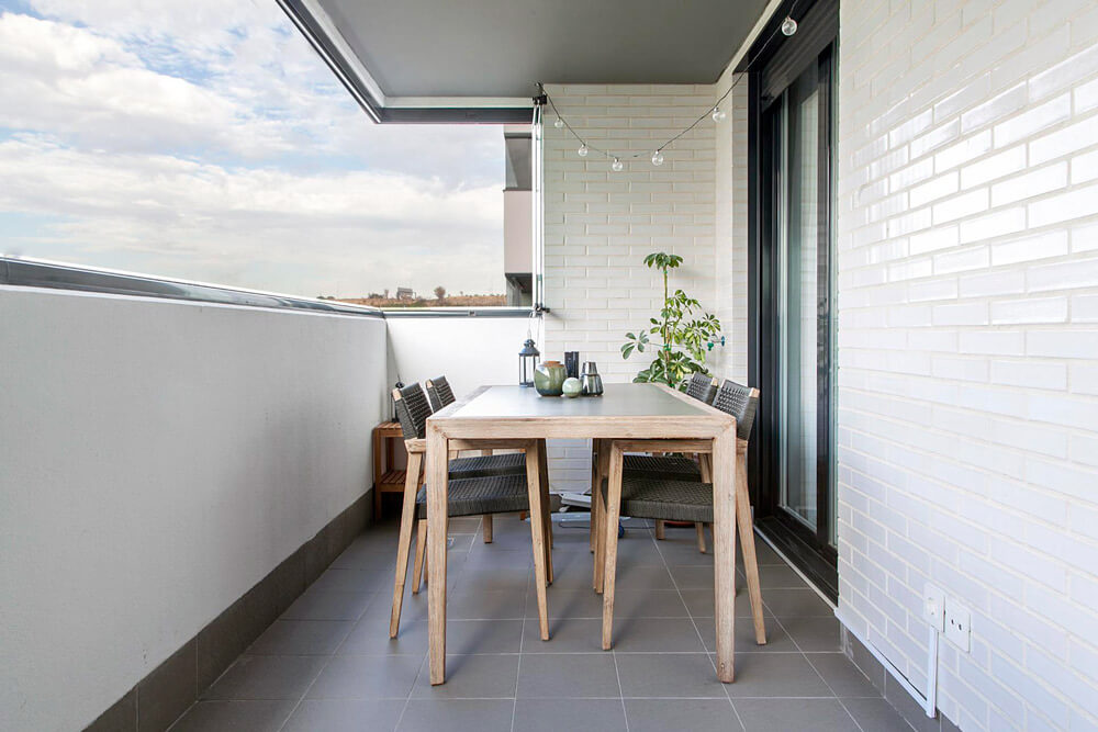 Proyecto de R de Room Amazing Homes. Terraza con mesa de comedor y sillas de madera maciza de acacia. Decoración de centro de mesa con jarrones de la firma danesa Bloomingville.