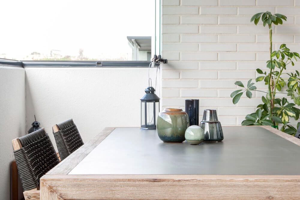 Proyecto de R de Room Amazing Homes. Terraza con mesa de comedor y sillas de madera maciza de acacia. Decoración de centro de mesa con jarrones de la firma danesa Bloomingville.