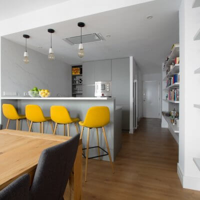 RdeRoom-MADERA reforma e interiorismo de vivienda para alquiler de lujo en Malasaña. Estar-comedor con cocina integrada. Mesa de madera. Taburetes tapizados.