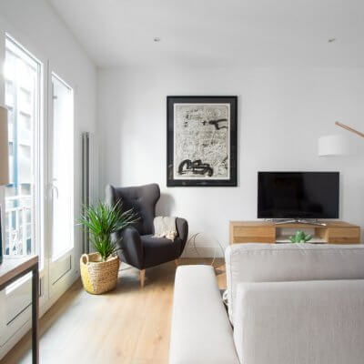 RdeRoom-MADERA reforma e interiorismo de vivienda para alquiler de lujo en Malasaña. Estar con orejero, sofá gris y mueble TV madera