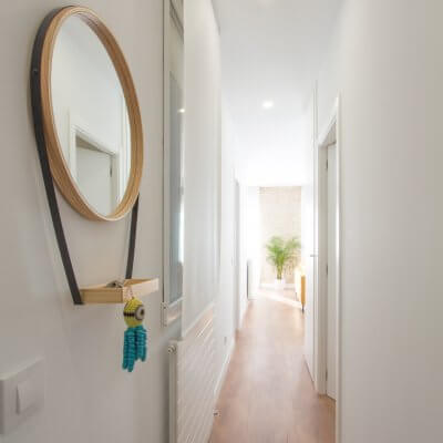 Proyecto de reforma de vivienda en Chamberí II (Madrid) de R de Room. Espejo circular con bandeja para recibidor. Suelo laminado de madera. Radiadores Runtal.