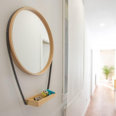 Proyecto de reforma de vivienda en Chamberí II (Madrid) de R de Room. Espejo circular con bandeja para recibidor. Suelo laminado de madera. Radiadores Runtal.