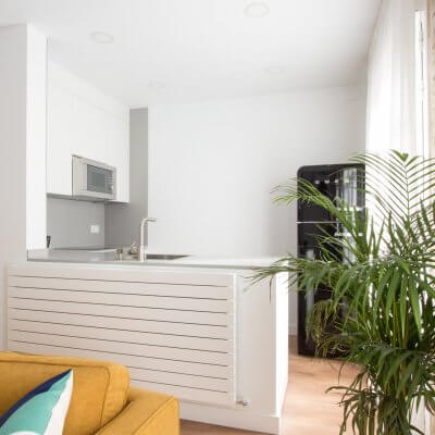 Proyecto de reforma de vivienda en Chamberí II (Madrid) de R de Room. Cocina abierta con península y frigorífico SMEG. Pared de ladrillo visto original. Radiador Runtal.