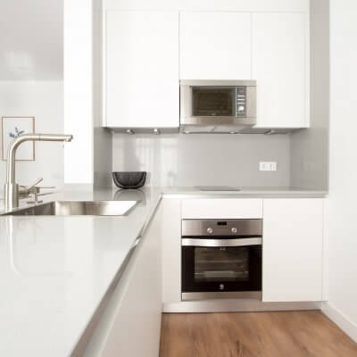 Proyecto de reforma de vivienda en Chamberí II (Madrid) de R de Room. Cocina abierta con península. Muebles blancos y encimera de Silestone en color gris claro.