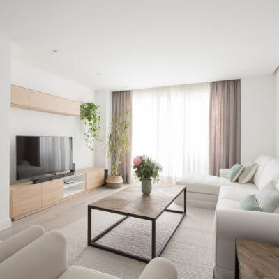 El mueble de TV de la serie NORWAY combina un mueble bajo de acabado roble y estantes blancos, con un módulo en altura, perfecto para ganar almacenaje extra. La gran alfombra lisa en tono beige es otro de los grandes protagonistas.