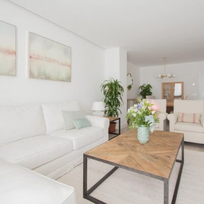 En la zona de estar, los protagonistas son los tonos neutros de los tapizados y textiles El sofá blanco desenfundable y las butacas gemelas tienen tapizados diferentes pero líneas redondeadas muy similares. Todo el mobiliario es de R de Room.