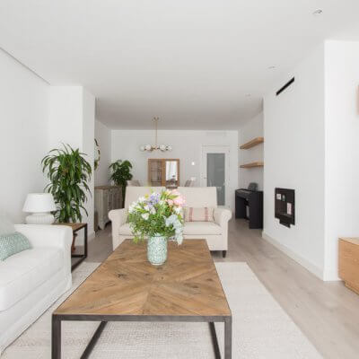 En la zona de estar, los protagonistas son los tonos neutros de los tapizados y textiles El sofá blanco desenfundable y las butacas gemelas tienen tapizados diferentes pero líneas redondeadas muy similares. Todo el mobiliario es de R de Room.