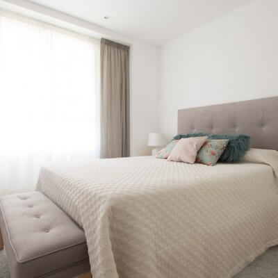 Diseñamos el dormitorio principal en tonos neutros. El cabecero de capitoné y el banco de pie de cama, ambos tapizados en tela gris de efecto aterciopelado, son los grandes protagonistas.