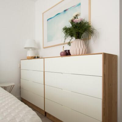 Dos cómodas de fondo reducido en chapado de roble y lacado blanco aumentan la capacidad de almacenamiento del dormitorio sin comprometer los pasos hacia la cama. Por sus dimensiones (96 x 98 x 40 cm), encajan en el hueco como un guante.