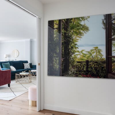 Recibidor de vivienda en Madrid. Cuadro de gran formato con paisaje. Puertas correderas, paredes blancas y suelo de madera de roble natural. Sofás de terciopelo rosa y verde. Proyecto de reforma e interiorismo de R de Room.