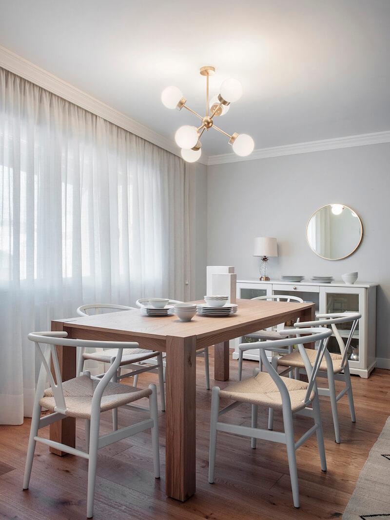 Comedor de vivienda en Madrid. Mesa rectangular de madera de roble extensible. Sillas CH24 blancas. Lámpara suspendida dorada. Comedor contemporáneo, luminoso y acogedor. Proyecto de reforma e interiorismo de R de Room.