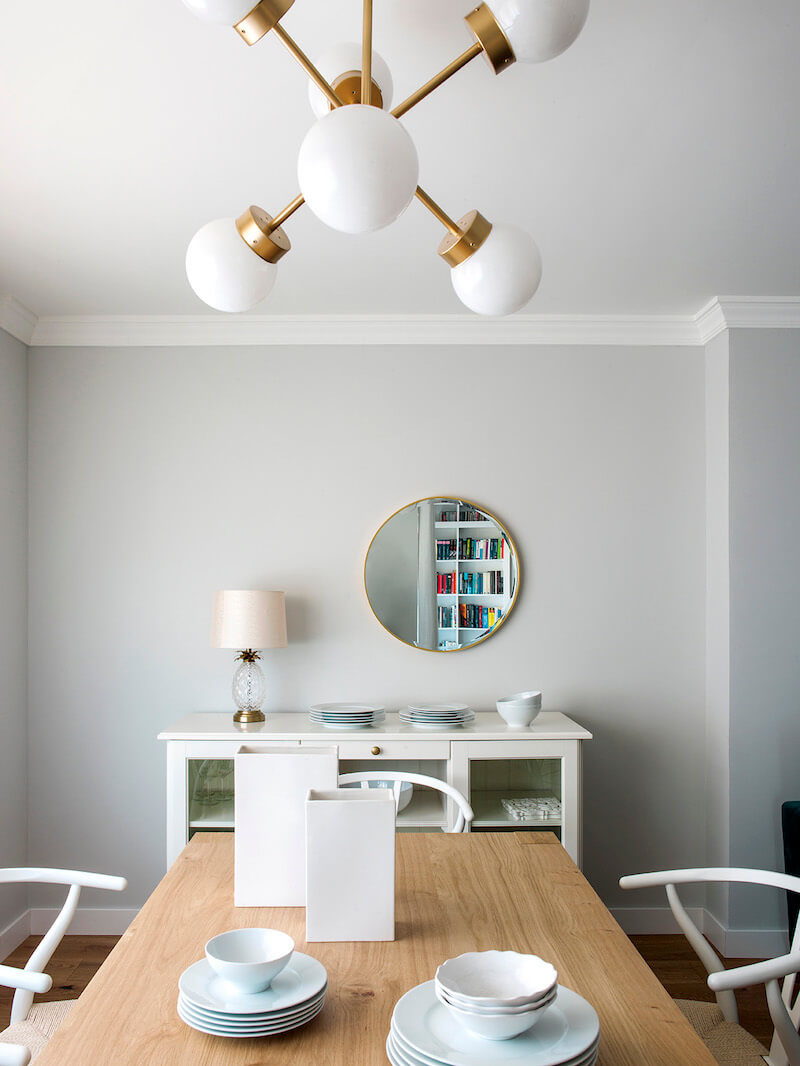 Comedor de vivienda en Madrid. Mesa rectangular de madera de roble extensible. Sillas CH24 blancas. Lámpara suspendida dorada. Comedor contemporáneo, luminoso y acogedor.