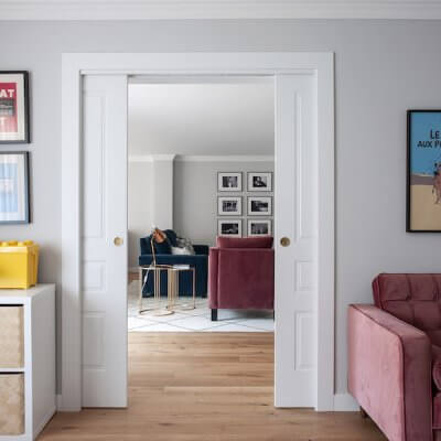 Salón de vivienda en Madrid. Espacios conectados a través de puertas correderas. Sofá de terciopelo rosa con capitoné. Cuarto infantil y zona de juegos. Mecedora Rocking Chair de Charles Eames. Proyecto de reforma e interiorismo de R de Room.