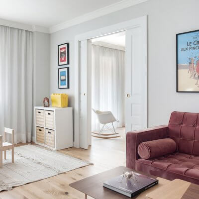 Salón de vivienda en Madrid. Espacios conectados a través de puertas correderas. Sofá de terciopelo rosa con capitoné. Cuarto infantil y zona de juegos. Mecedora Rocking Chair de Charles Eames. Proyecto de reforma e interiorismo de R de Room.