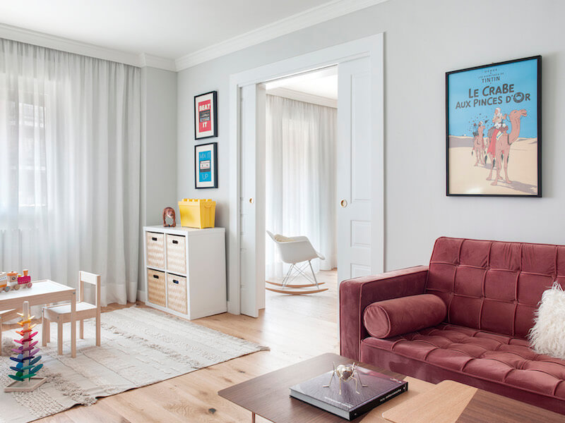 Salón de vivienda en Madrid. Espacios conectados a través de puertas correderas. Sofá de terciopelo rosa con capitoné. Cuarto infantil y zona de juegos. Mecedora Rocking Chair de Charles Eames. Proyecto de reforma e interiorismo de R de Room.