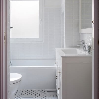 Baño para niños. Zócalo de azulejo esmaltado biselado tipo metro en color blanco. Pared pintada en color amarillo. Degradado de pintura en pared. Mueble de lavabo estilo retro. Baño luminoso. Proyecto de reforma e interiorismo de R de Room.