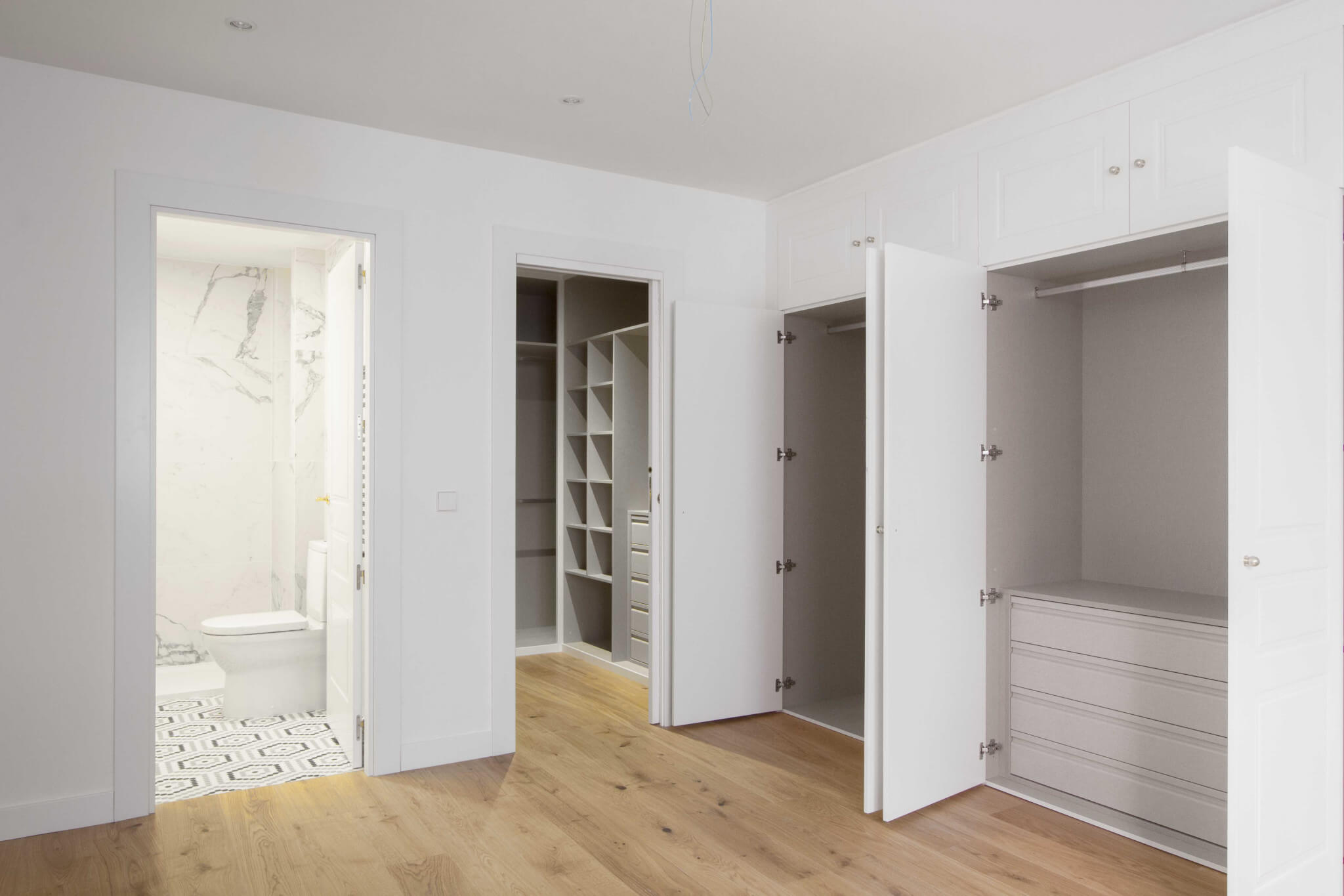 Dormitorio principal con vestidor y baño en suite. Almacenamiento de dormitorio principal. Reforma de vivienda en Chamberí, Madrid. Armarios empotrados a medida. Proyecto de reforma e interiorismo de R de Room.