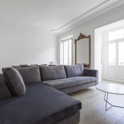 Proyecto de reforma en Chamberí (Madrid) de R de Room. Salón minimalista. Molduras. Sofá gris. Espejo dorado.