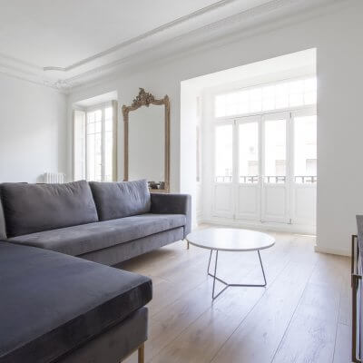 Proyecto de reforma en Chamberí (Madrid) de R de Room. Salón minimalista. Molduras. Sofá gris. Espejo dorado.