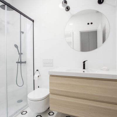 Proyecto de reforma en Chamberí (Madrid) de R de Room. Baño en blanco y negro. Suelo teselas Hisbalit. Grifería, mampara y focos negros.