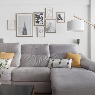 Interiorismo de vivienda_estar comedor-sofá gris-ambiente cálido-collage de cuadros