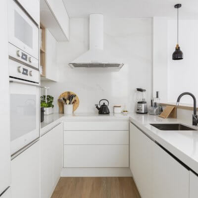 Cocina blanca con península abierta al salón. Detalles negros en grifo, lámparas y decoración. Proyecto de R de Room.
