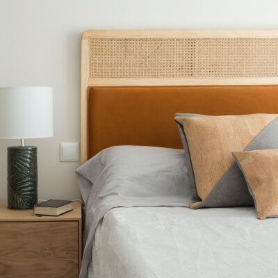Dormitorio con mesitas de noche de madera y cabecero de rejilla y terciopelo caldera. Proyecto de R de Room.