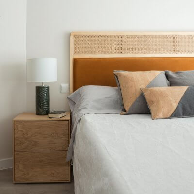 Dormitorio con mesitas de noche de madera y cabecero de rejilla y terciopelo caldera. Proyecto de R de Room.