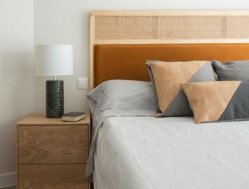 Dormitorio con mesitas de noche de madera y cabecero de rejilla y terciopelo caldera. Proyecto de R de Room.