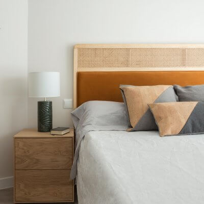 Dormitorio con mesitas de noche de madera y cabecero de rejilla y terciopelo caldera. Proyecto de R de Room.