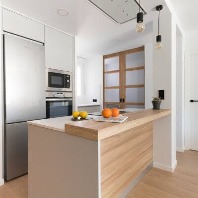 Cocina abierta gris claro y madera. Puertas con cuarterones. Proyecto R de Room.
