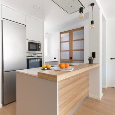 Cocina abierta gris claro y madera. Puertas con cuarterones. Proyecto R de Room.
