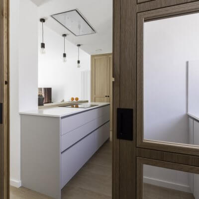 Cocina abierta gris claro y madera. Puertas con cuarterones. Proyecto R de Room.