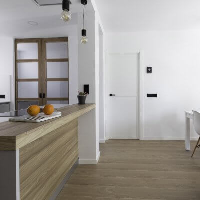 Cocina abierta gris claro y madera. Puertas con cuarterones. Proyecto R de Room.