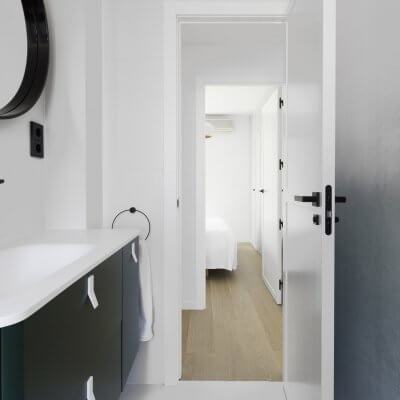 Baño principal con mueble y mural verdes y toques negros. Proyecto R de Room.