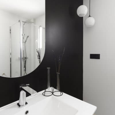 Baño de cortesía. Pintura negra y azulejo geométrico en b&n. Proyecto R de Room.
